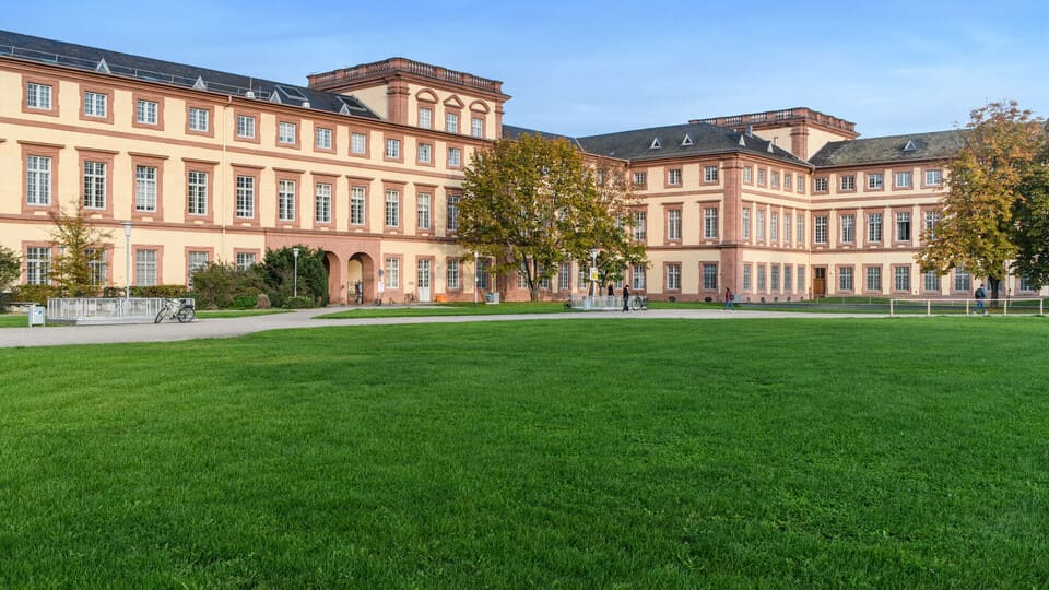 Schloss der Uni Mannheim mit Rasenfläche im Vordergrund.